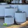 Set of gray cylindrical planters with ribbed texture on a concrete surface, brand 'landscape.com.au' visible.